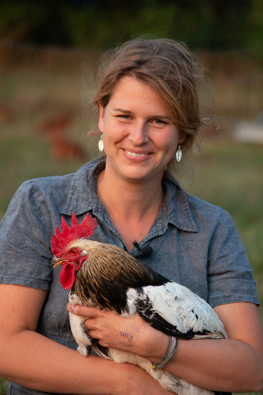 Agricultrice avec un coq dans les bras.