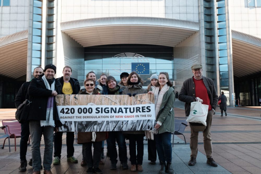 Banderole avec le message "420 000 signatures contre la déréglementation des nouveaux OGM en Europe" tenue par les organisations signataires de la pétition.